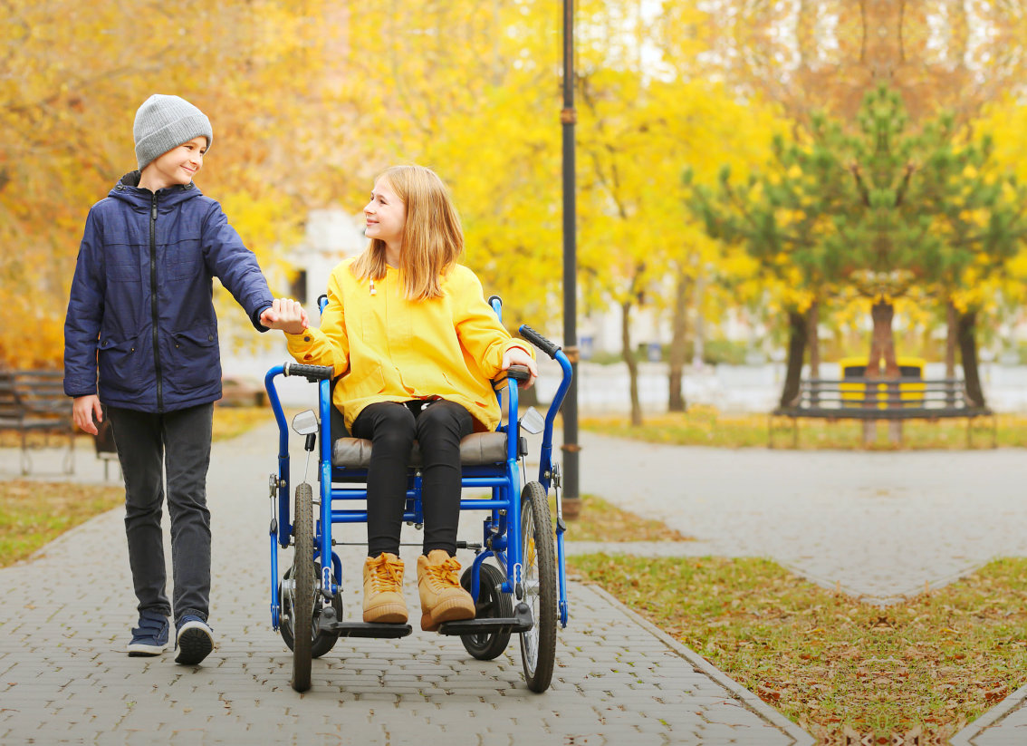 a boy with his sister on a wheelchair smiling at each other