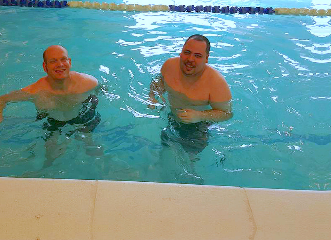 two men smiling on the swimming pool