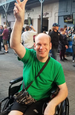 man on the wheelchair smiling with peace sign on his fingers